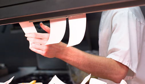 Chef looking over active food orders.